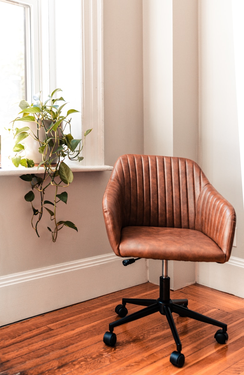 brown and black rolling chair beside green plant